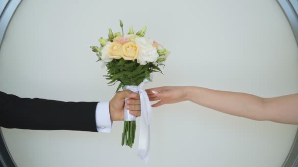 Dłonie młodej pary przekazującej sobie bukiet ślubny. Nierozpoznany pan młody daje kwiaty swojej pięknej pannie młodej. Nowożeńcy świętujący małżeństwo. Symbol ślubu. Powolny ruch Zamknij — Wideo stockowe