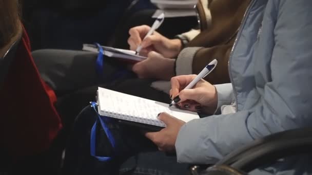 Ein unkenntlich gemachter Student in schwarzem Hemd schreibt Notizen zur Vorlesung. Professioneller Journalist interviewt und schreibt Text in Notizbuch. Der Mensch führt Tagebuch. Bildungskonzept. Zeitlupe Nahaufnahme — Stockvideo