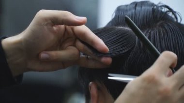Berber dükkanındaki saç kesimine yakından bak. Profesyonel berber, erkek müşterinin saçını tarıyor ve kesiyor. Kuaför moda saç stili yapıyor. Saç bakımı kavramı. Yavaş çekim