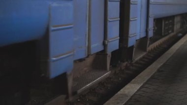 Yolcu treni bir kameranın yanından geçiyor ve istasyona varıyor. Demiryolu boyunca ilerleyen trenin dönen çelik tekerleklerini kapatın. Ulaşım ve seyahat kavramı. Düşük Görünüm Yavaşlatıcı