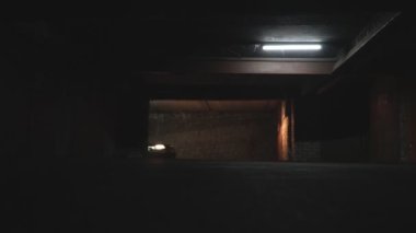 Park yerine giderken parlak farları olan bir araba. Otomobil karanlık yeraltı garajına giriyor. Yavaş çekim