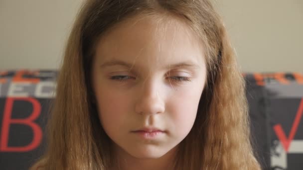 Pequeño niño decepcionado sentado en el sofá y mirando a la cámara. Retrato de niña infeliz con el pelo rubio en el interior. Acercamiento de las emociones de la niña con expresión dolorosa en su rostro — Vídeo de stock