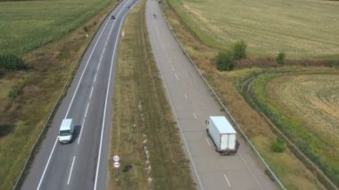 Düz yolda giden ve malları taşıyan kargo karavanı olan kamyonun hava görüntüsü. Kameralar taşra otobanından geçen teslimat kamyonunu izliyor. Kırsal kesimde trafiğin üzerinde uçmak