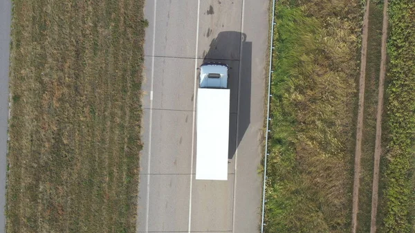空の道路を走行し 貨物を輸送する白い貨物トレーラーとトラックの空中ビュー 田舎の高速道路を通って移動する1つの配達のローリーを飛び越える 論理的概念 トップ表示 — ストック写真