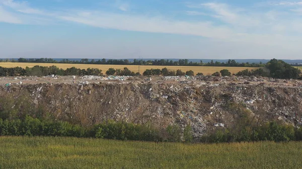 Aerial view of rubbish pile lying among field in rural. Flying over industrial trucks dumping trash at open and freely available places at nature. Environmental pollution problem. Dolly shot.