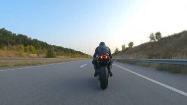 Motorcu, boş köy yolunda motorsikletle hızlanıyor. Sonbahar otobanında modern spor motosikletinde hızlı giden bir adam. Yolculuk sırasında bisiklet süren adam. Özgürlük ve macera kavramı. Hava görüntüsü