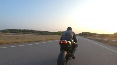 Günbatımında otoyolda hızlı giden bir adamın hava görüntüsü. Motosikletli, kır yolunda motosikletiyle yarışıyor. Yolculuk sırasında bisiklet süren adam. Özgürlük ve macera kavramı