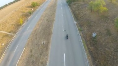 Sonbahar otobanında modern motorsiklet süren bir adamın havadan çekilmiş fotoğrafı. Motosikletli, kır yolunda motosikletiyle yarışıyor. Yolculuk sırasında bisiklet süren adam. Özgürlük ve macera kavramı. Görünümün üstünde