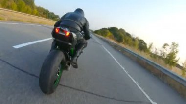 Otobanda motosiklet süren motosikletli bir motorcunun kamera görüntüsü. Motosikletli gün batımında kır yolunda motosikletiyle yarışıyor. Yolculuk sırasında bisiklete binen adam. Özgürlük ve macera kavramı