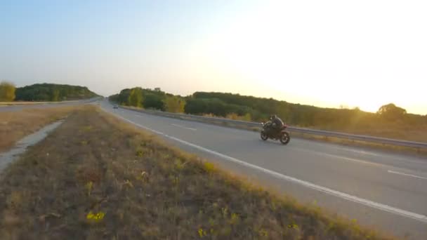 Motorkář řídí motocykl během výletu při podzimním západu slunce. Člověk jezdit rychle na moderní sportovní motocykl na dálnici. Motorkář závodní kolo na venkovské silnici. Pojem dobrodružství. Letecký snímek — Stock video