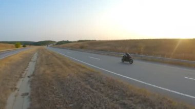 Motosikletlinin hava görüntüleri Autumn Highway 'de modern spor motosiklet sürüyor. Motosikletli gün batımında kır yolunda motosikletiyle yarışıyor. Yolculuk sırasında bisiklet süren bir adam. Özgürlük ve macera kavramı