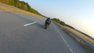 Otobanda motosiklet süren motosikletli bir motorcunun kamera görüntüsü. Motosikletli gün batımında kır yolunda motosikletiyle yarışıyor. Yolculuk sırasında bisiklete binen adam. Özgürlük ve macera kavramı