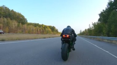 Sonbahar otobanında motosiklet süren motosikletliyi takip edin. Motosikletli, kır yolunda motosikletiyle yarışıyor. Yolculuk sırasında bisiklete binen adam. Özgürlük ve macera kavramı. Hava görüntüsü