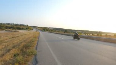 Sonbahar otobanında modern motosiklet kullanan motorcuya hava manzarası. Motosikletli güneşli bir günde kır yolunda motosikletiyle yarışıyor. Yolculuk sırasında bisiklet süren bir adam. Özgürlük ve macera kavramı