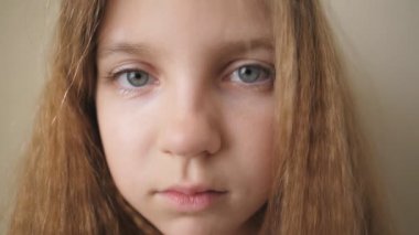 Kapalı mekandaki kameraya bakan çaresiz çocuğun kadın yüzünü kapatın. Üzgün küçük bir çocuğun hayal kırıklığına uğramış bakışları. İçinde hüzünlü bir ifade olan küçük sarışın kızın portresi.