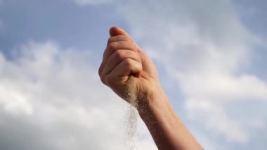 Nazikçe kumları salıyor, bir düğün sırasında bir bağ anını gösteriyor, yukarısında yumuşak bulutlar, sakin bir açık havada neşe ve kutlama hissi uyandırıyor.