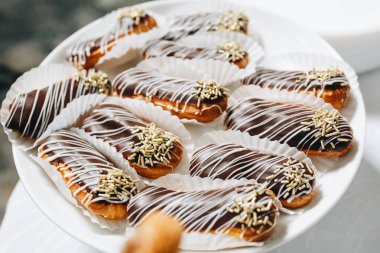 Profiterol ve eklerleri siyah beyaz beyaz bir tabağa çikolata ile,