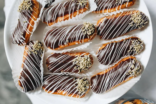 Profiterol ve eklerleri siyah beyaz beyaz bir tabağa çikolata ile,