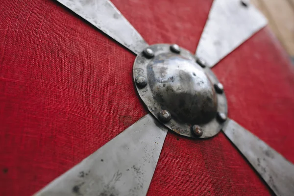 The texture of iron metal silver strong old medieval beautiful red round battle shield armor for protection with pattern. Background