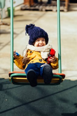 mutlu çocuk ceket şapka ve atkı bir salıncak üzerinde sürme