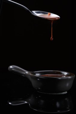 Erimiş sütlü kahverengi çikolata bir kaşık dökülen, siyah izole