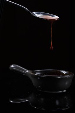 Erimiş sütlü kahverengi çikolata bir kaşık dökülen, siyah izole
