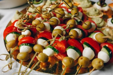 Yemek masası, ziyafette sofraya çeşitli atıştırmalıklar koydu. Soğuk aperatifler, kanepeler, içecekler, yakın çekim. Yan görüş. Ziyafet masası.
