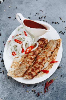 beyaz tabakta ketçap ile kebap eti 