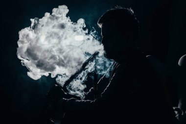karanlık bir arka plan closeup üzerinde duman soluma bir adamın silueti