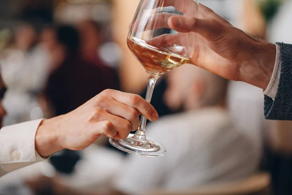 De mano en mano pasar una hermosa copa de vino blanco en la cena en un restaurante —  Fotos de Stock