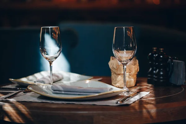 Vajilla Vasos, tenedor de flores, cuchillo servido para la cena en el restaurante con interior acogedor —  Fotos de Stock