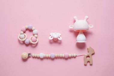 Bebek aksesuarları konsepti: Bağlayıcı, tırtıl oyuncağı ve bebek emziği, pembe arka planda fotokopi alanı, üst görünüm, düz yatış