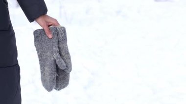 Girl in warm winter clothes on a snowy background.The theme of the imminent onset of winter.