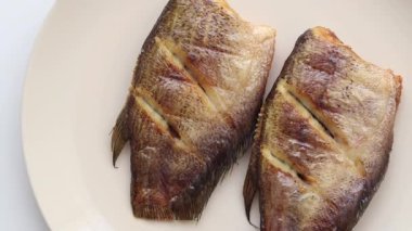 Kızarmış gourami 'nin beyaz arka planda bir tabakta üst görüntüsü. Taylandlılar genellikle lezzetli kurutulmuş balık yemekleri yapmak için kullanırlar..