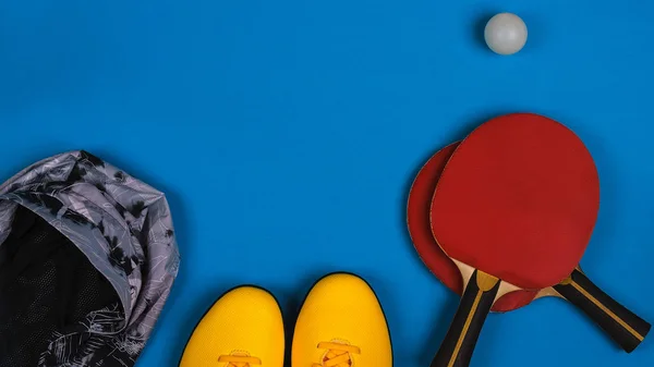 Vista superior de la composición deportiva con zapatillas, chaqueta, cohete de tenis con bola sobre el fondo azul brillante, horizontal —  Fotos de Stock