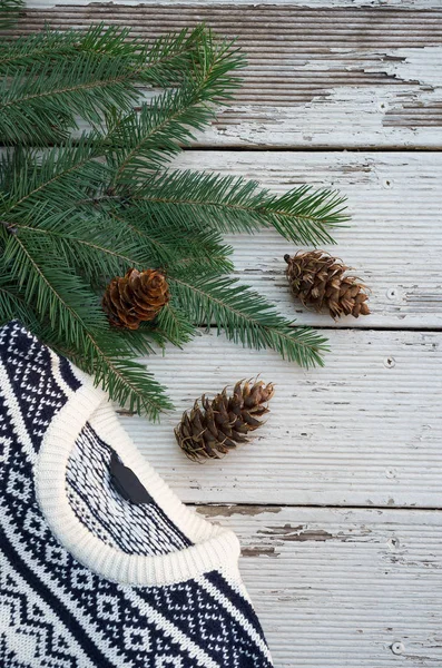 Белый и черный вязаный свитер на зимнем рождественском узоре на деревянном фоне с ветвями ели. Шерсть . — стоковое фото