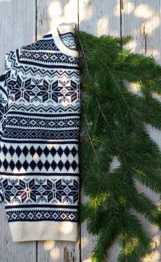 Beyaz ve siyah örme yün kazak üzerine kış Noel desen ray güneşin altında ahşap gri arka plan üzerinde köknar ağacının dalları ile üzerinde üstten görünüm.