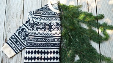 Beyaz ve siyah örme yün kazak üzerine kış Noel desen ray güneşin altında ahşap gri arka plan üzerinde köknar ağacının dalları ile.