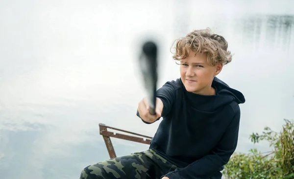 Retrato de un adolescente pescando en la orilla del río o lago. Lindo chico con pelo rizado — Foto de Stock