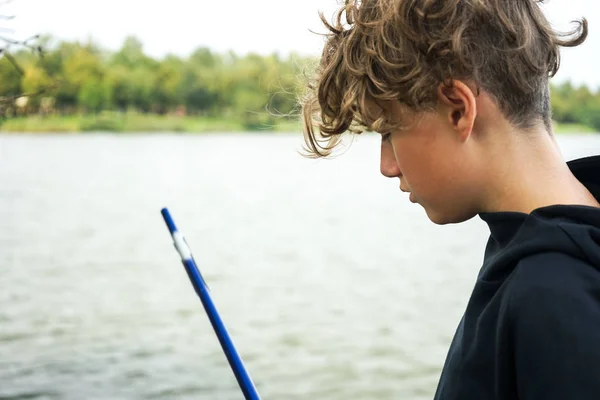 Retrato de un adolescente pescando en la orilla del río o lago. Lindo chico con pelo rizado — Foto de Stock