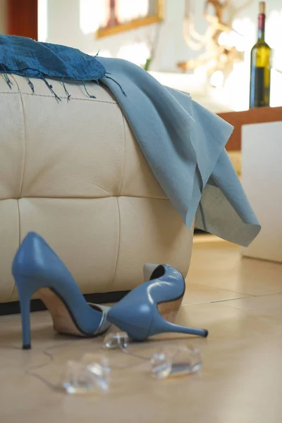 Partido colección de ropa femenina zapatos de vestir azul accesorios joyería en sofá beige en el suelo en el interior con vino botella. Después de la celebración de vacaciones. Fiesta de Navidad Feliz Año Nuevo concepción —  Fotos de Stock