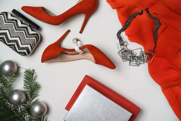 Düz Noel ve yeni yıl partisi kıyafet kompozisyon kırmızı ayakkabı aksesuarları takı debriyaj köknar ağacı topları beyaz arka plan ile yattı. Parti Tarih gece anlayışı. Üstten görünüm, dikey, yatay
