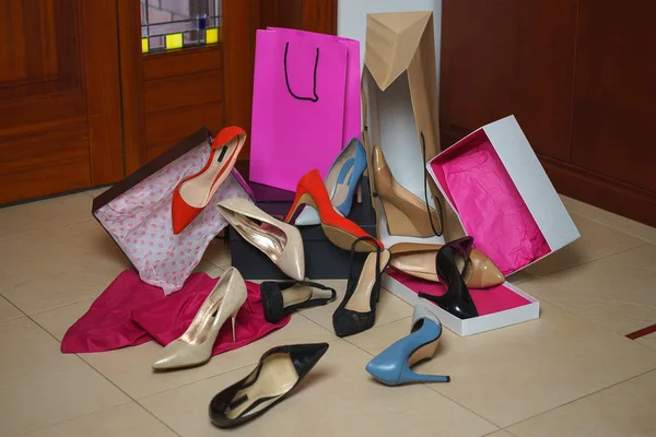 Shoes heels from shop or store in home interior background. Pile of colorful assorted footwear in floor with boxes and package bag. Sale Shopping Black Friday concepts.