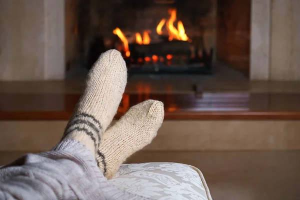 Feet in woollen socks and knitted plaid in front of the fireplace. Close up on feet. Cozy relaxed magical atmosphere home interior. Christmas New Year winter holidays concept. Horizontal — Stock Photo, Image