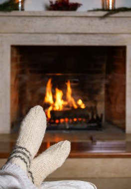 Sıcak beyaz tanınmaz halde kadın ya da şöminenin önünde rahat ekose ile oturan adam ayaklarına çorap ördü. Rahat rahat büyülü atmosferi ev iç. Yılbaşı yeni yıl kış konsepti.
