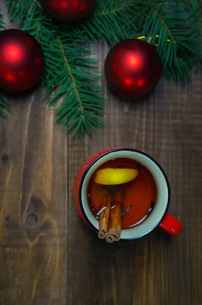 Taza de té aromático caliente con palitos de canela y limón con ramas de árbol de Navidad y bolas rojas sobre fondo de mesa de madera. Navidad Año Nuevo concepto de vacaciones de invierno. Piso tendido, vista superior — Foto de Stock