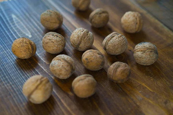 Raw organic walnuts in the shell on old brown wooden background in rustic style. Harvest nuts from country. Healthy ingredients for diet. Close up. — Stock Photo, Image
