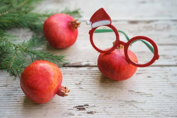 Rojo vivo granadas de Navidad gafas rojas verdes gafas blancas con marco decorativo de vacaciones y ramas de abeto sobre fondo de madera gris. Navidad concepto de diseño de Año Nuevo. Copiar espacio — Foto de Stock
