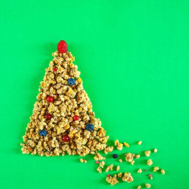 Noel sağlıklı yaşam düzeni granola veya müsli çilek ve ahududu yeşil zemin üzerine üstte topları ile Noel ağacı şeklinde. Yeni yıl kavramı diyet sağlıklı kahvaltı için. Düz yatıyordu