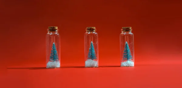 Árvore de Natal com neve em frasco de vidro pequeno no fundo vermelho. Inverno criativo fundo Ano Novo. Deitado plano, vista superior. Conceito mínimo de Ano Novo . — Fotografia de Stock